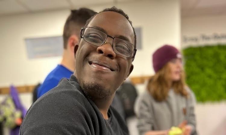 An Adults in Motion member in glasses smiling over his shoulder at a science activity